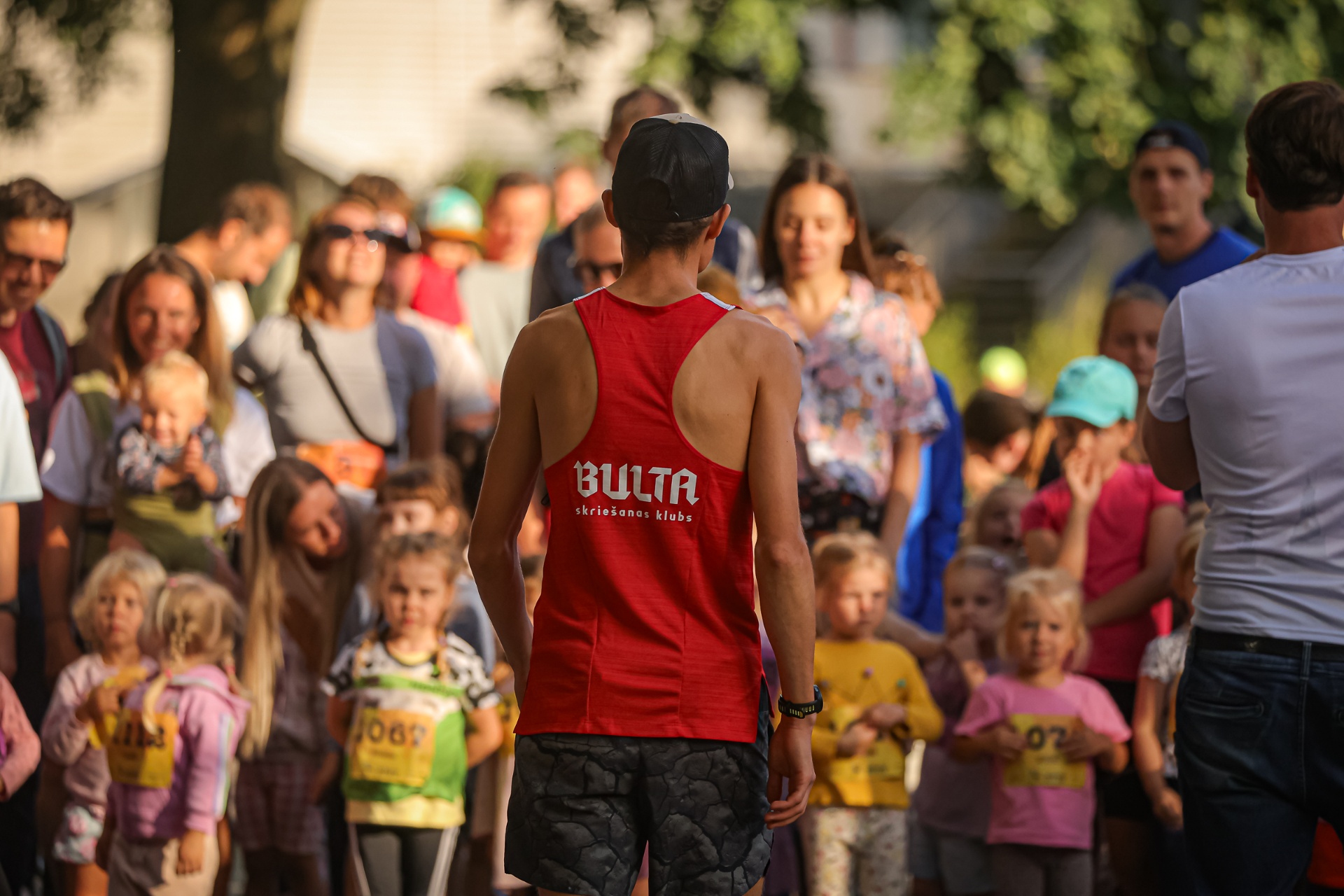 BULTA runner facing a crowd of children and supporters